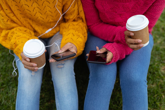 Two young women holding smartphones outdoors