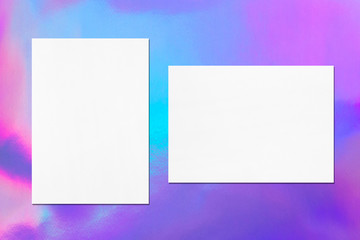 Two empty white vertical and horizontal rectangle poster mockup with soft shadow on holographic background. Flat lay, top view