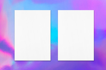 Two empty white vertical rectangle poster mockup with soft shadow on holographic background. Flat lay, top view