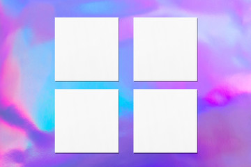 Four empty white square flyer or business card mockups with soft shadows on holographic background. Flat lay, top view