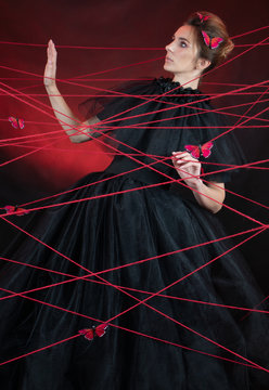 Art photo of a girl tangled in red threads of a web