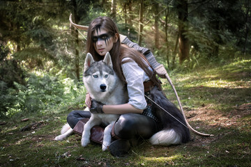 Art photograph of a hunter with a bow and a wolf in a sunlit forest