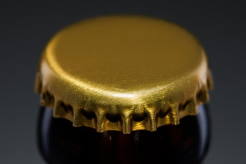 gold cap of beer bottle on dark background