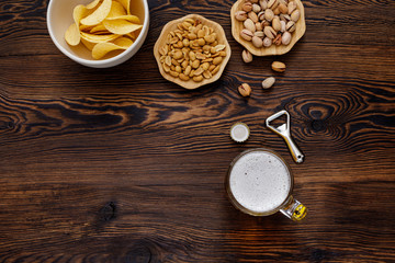 Beer glass with bottle cap and snack on wood background. top view. copy space