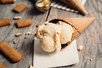 studio shot of tasty ice cream in cone on rustic wooden table