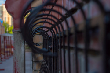 Part of a black metal curly fence. Selective focus. View along.