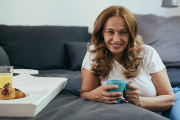 mid age woman enjoying morning coffee in her home