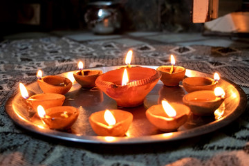 Macro shots of diyas being lit by hand or candle for the hindu religious festival of Diwali. These colorful earthern pots hold oil and a cotton wick to light