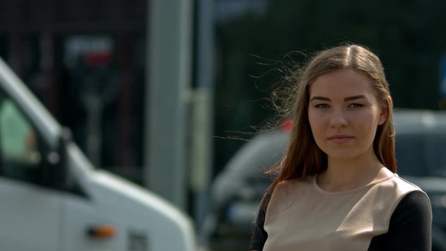 Confident young business owner looking into the camera with vehicles passing by near a busy street crossing. Concept of a modern entrepreneur.
