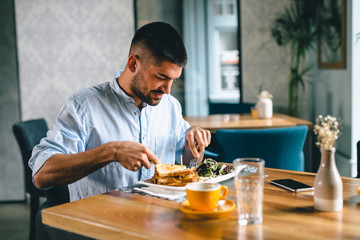 Obraz na płótnie Canvas young man eating alone in restaurant