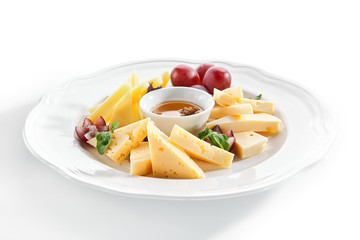 Cheese Platter with Honey, Nuts and Grapes on White Restaurant Plate