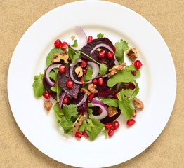 Beetroot salad with arugula, walnuts and pomegranate seeds, top view 