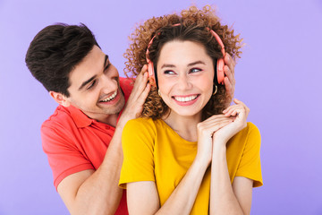 Portrait of young positive couple smiling while listening to music together with headphones