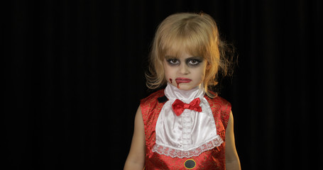 Dracula child. Girl with halloween make-up. Vampire kid with blood on her face