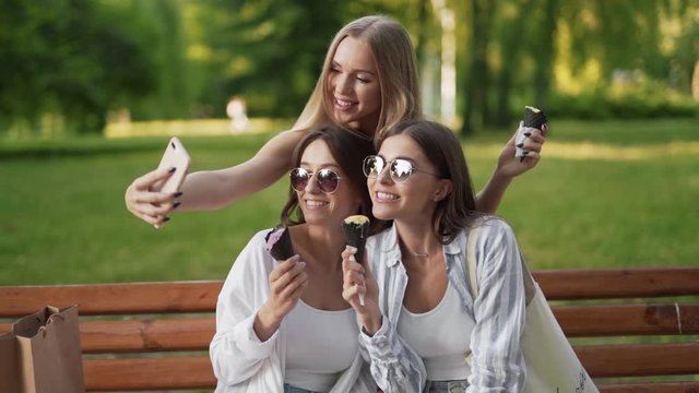 Three young girls taking a selfie while eating ice cream in the park