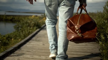 Man carries a brown bag on a long jetty towards lakeside