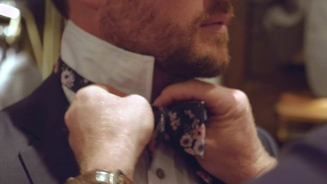 Father of the groom doing up his bowtie on his wedding day