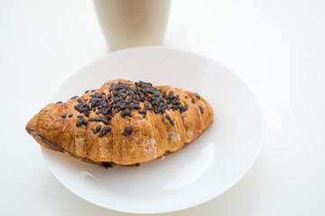 sweet chocolate croissant on white plate and cup 
