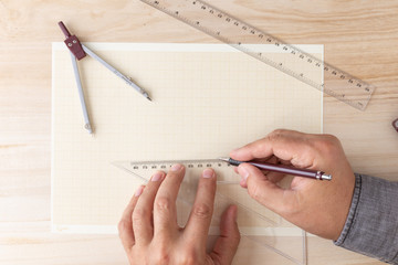male hands on a graph paper with rulers and a compass