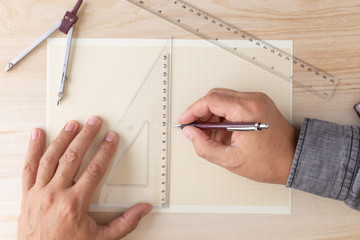 male hands on a graph paper with a pencil ruler square and compass