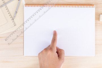 left male hand pointing to an empty page of a spiral bound notebook