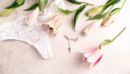 lilies and white colour panties on a light marble backdrop, sensual flat  lay