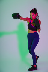 Beautiful strong fitness woman boxer isolated with led flash lights make boxing exercises.