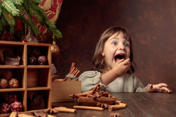 Little girl in an vintage linen dress near the table with sweets. Genre portrait in retro style.