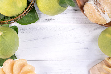 Fresh peeled pomelo, grapefruit, shaddock with green leaf on bright wooden plank table. Seasonal fruit near mid-autumn festival, top view, copy space