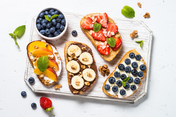 Sweet toast assortment with fresh fruit and berries on white.