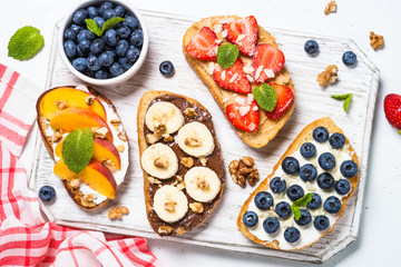 Sweet toast assortment with fresh fruit and berries on white.