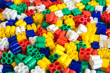Multicolored plastic building blocks of the designer. Background of plastic colored details building blocks. Parts of bright small spare parts for toys. Close up.