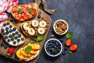 Sweet toast assortment with fresh fruit and berries on black.