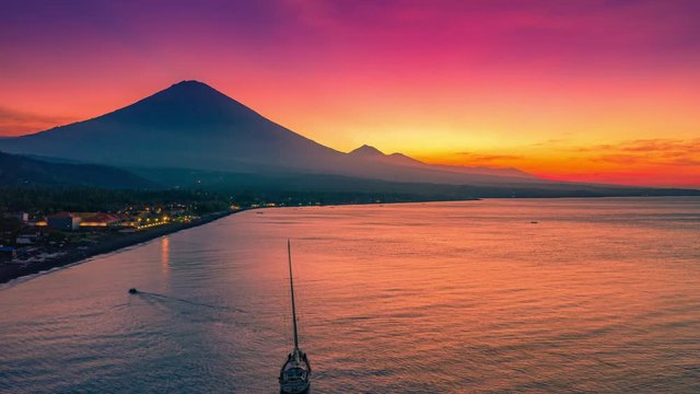 Beautiful Sunset in Amed on the beach with local boats and view of Agung volcano in Bali, Indonesia. Aerial Timelapse 4K