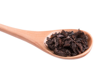 Leaves of black tea. Black tea in a spoon isolate on a white background.