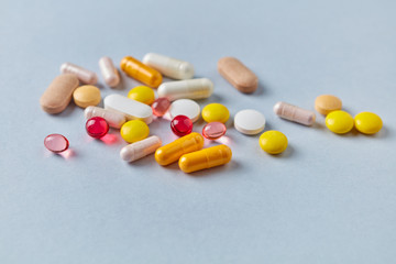 Vitamins and supplements on bright paper background. Concept for a healthy dietary supplementation. Close up. Copy space. 