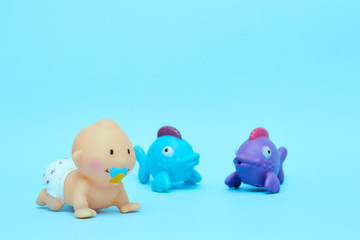 Vintage crawling doll for swimming with colored fish on a blue background, a rubber doll of a little boy. Copy space isolator. children's toys for children.