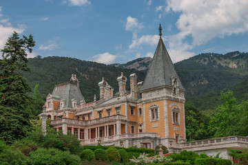 Fototapeta na wymiar Old manor, castle among forest trees and near Crimean mountains in the beginning of summer