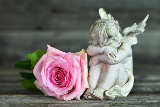 Guardian angel and rose on wooden background
