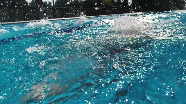 Professional swimmer training breaststroke at pool outdoor slow motion