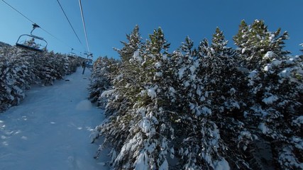 Riding ski chair lift through snowy forest