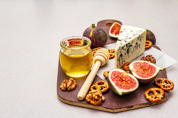 Cheese platter (board) with blue cheese, honey, walnuts, figs, pretzels