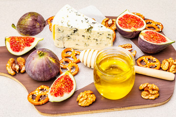 Cheese platter (board) with blue cheese, honey, walnuts, figs, pretzels
