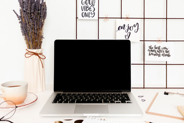Workspace with mood board, laptop, stationery, mug of coffee and lavender flowers
