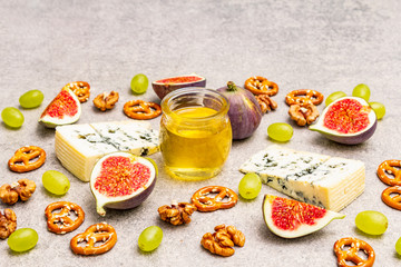Fototapeta na wymiar Cheese appetizer selection or wine snack set. Blue cheese, figs, honey, walnuts, pretzels