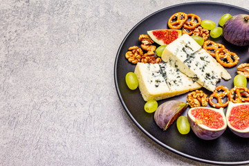 Cheese plate with blue cheese, walnuts, figs, grapes, pretzels