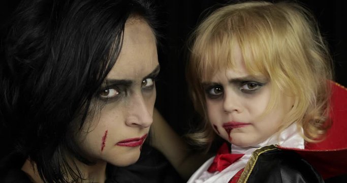 Woman and child dracula. Halloween vampire make-up. Kid with blood on her face