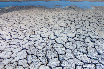 Heat, drought, disaster, saline soil, dry riverbed, blue sky reflected in the remnants of water. Bright, beautiful natural landscape. Close-up, background, Wallpaper, design. Selective focus.