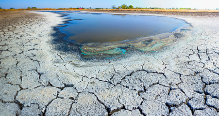Panorama. Heat, drought, disaster, saline soil, dry riverbed, blue sky reflected in the remnants of...