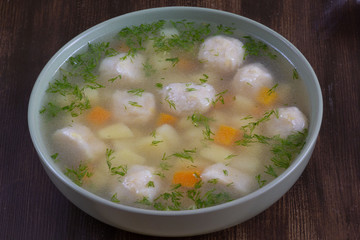 Top view of soup in bowl with dumplings on wooden background
